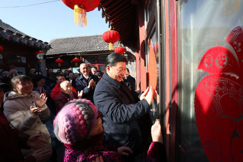 2019年2月1日上午，習近平在北京前門東區(qū)草廠四條胡同32號院，高興地拿起一幅“?！弊?，親自貼到門上，給這里的老街坊們拜年。新華社記者 鞠鵬 攝